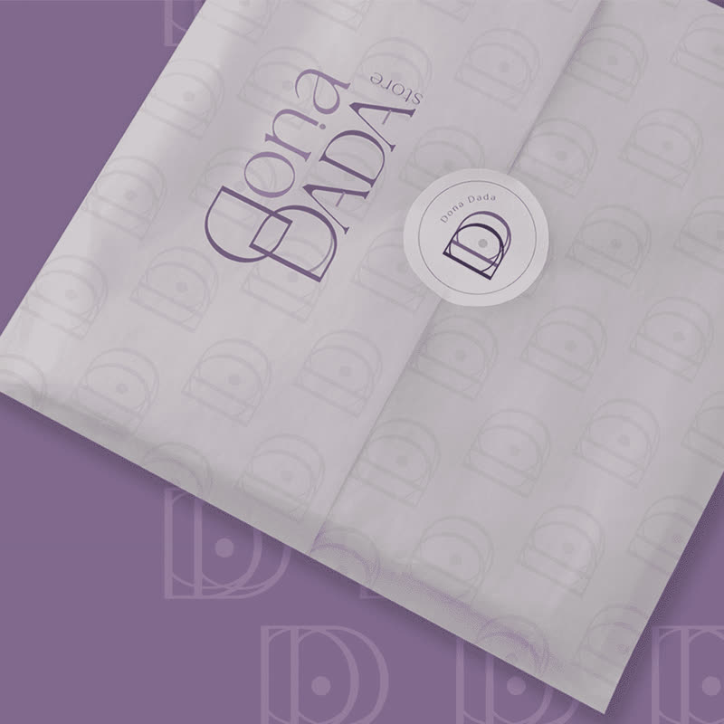 Papel de seda lilás estampado com o monograma da Dona Dada Store e adesivo redondo com a marca